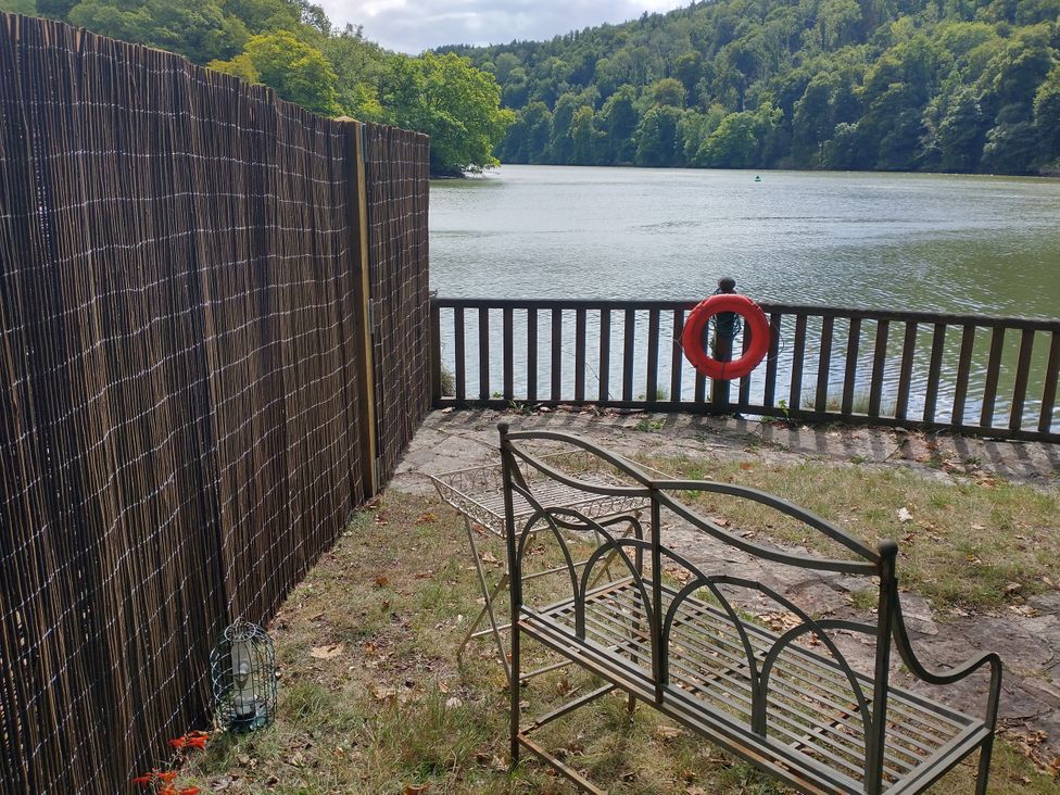 A view of a lake with a metal bench and a life buoy at The Sharpham Boat House in Ashprington