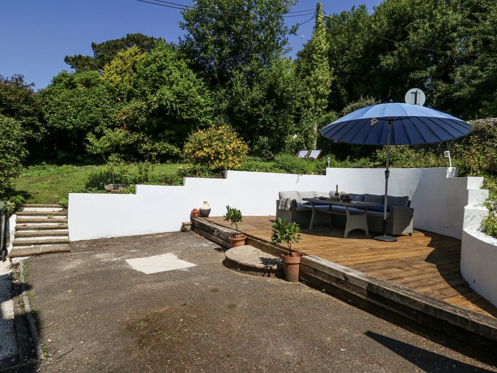 A garden with a patio and an umbrella at Happiness Cottage in Piddlehinton