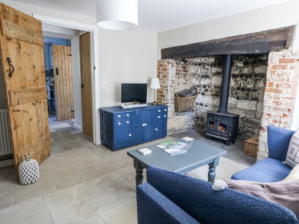 A living room with a wood stove and television at Happiness Cottage Piddlehinton