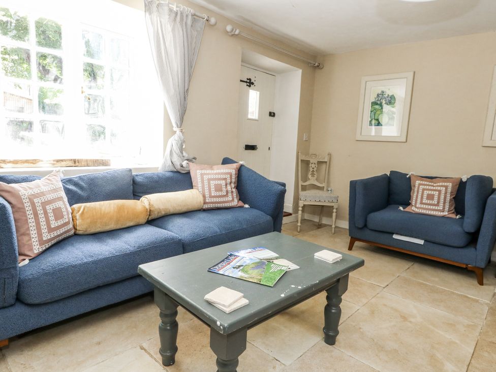 A living room with blue sofas and a coffee table at Happiness Cottage in Piddlehinton