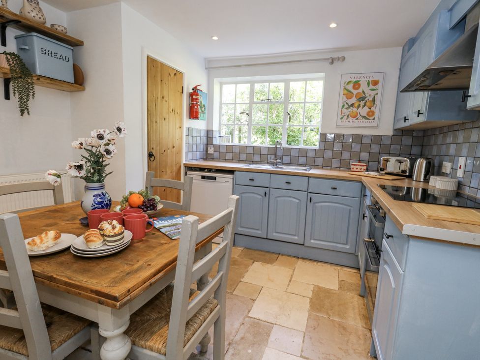 A kitchen with a table and chairs at Happiness Cottage in Piddlehinton
