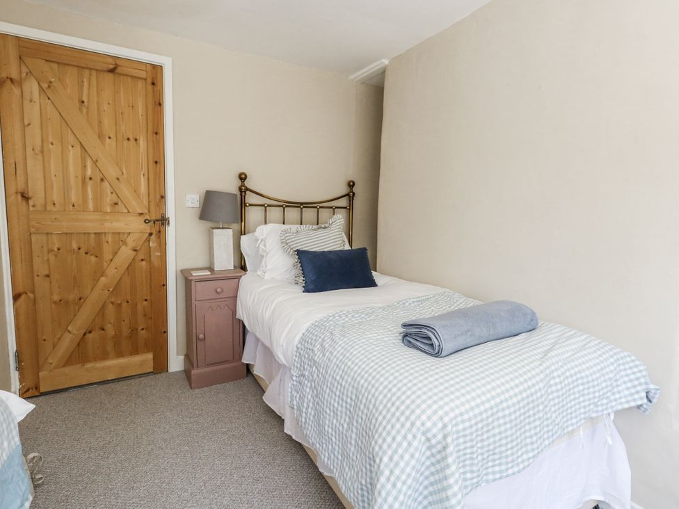 A bedroom with a single bed and wooden door at Happiness Cottage in Piddlehinton