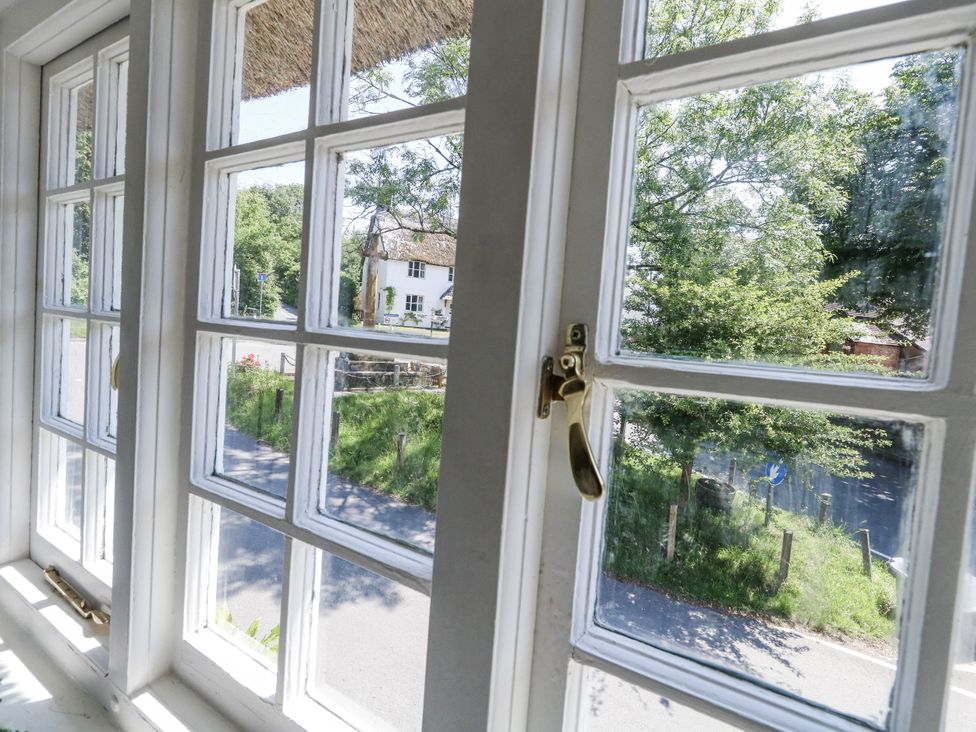 A window showing a view of a road and trees at Happiness Cottage in Piddlehinton