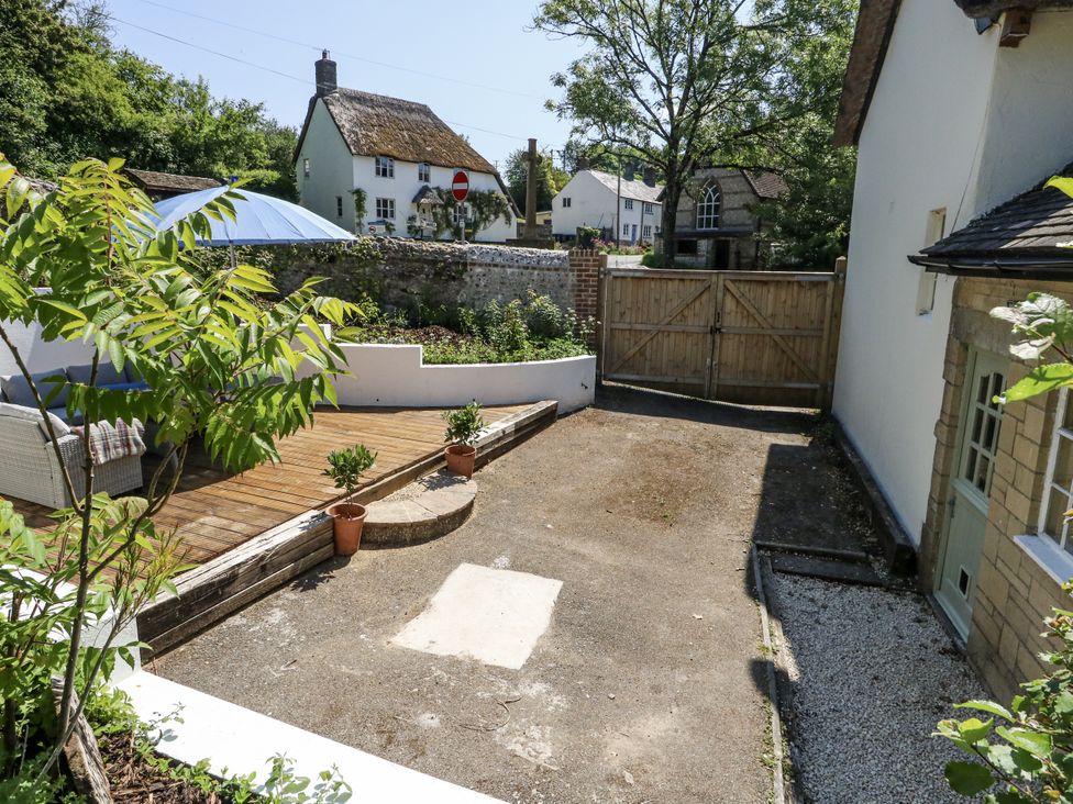 A garden with decking and potted plants at Happiness Cottage in Piddlehinton