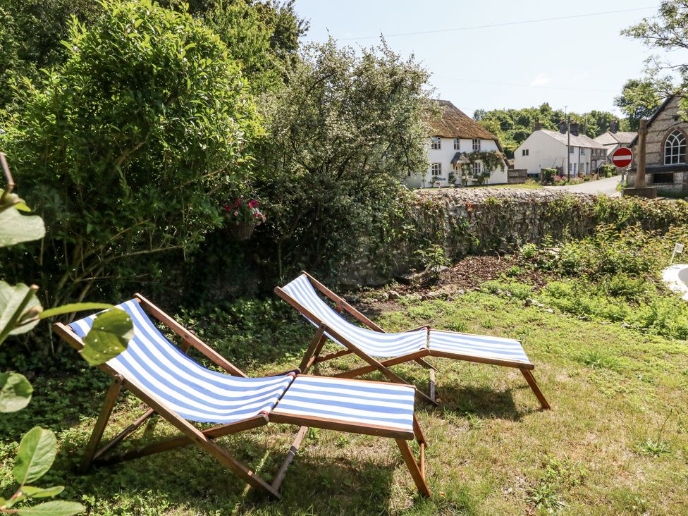 A garden with deck chairs and greenery at Happiness Cottage in Piddlehinton