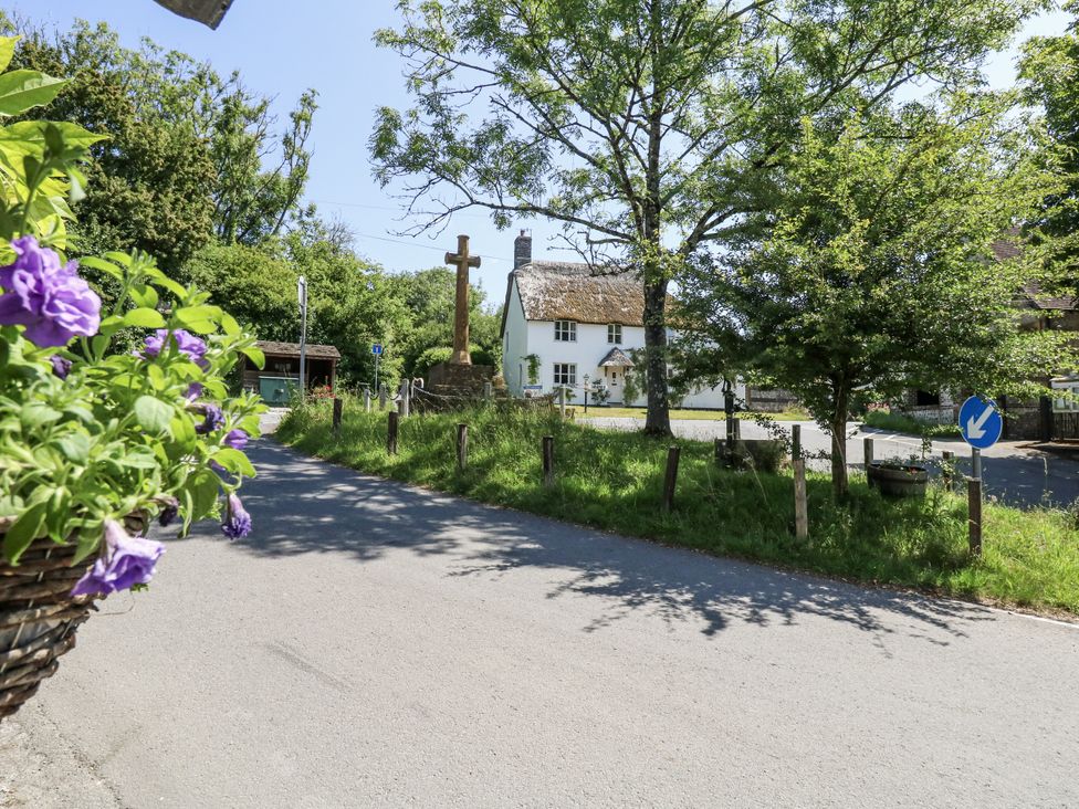 A view of a house with a cross and trees at Happiness Cottage in Piddlehinton