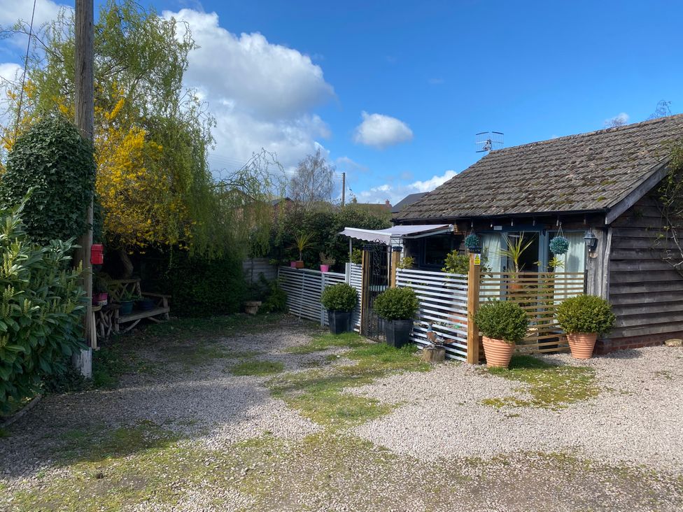 An outdoor area with a building, fence, and flowerpots at The Pheasant's Nest in Welland near Upton Upon Severn