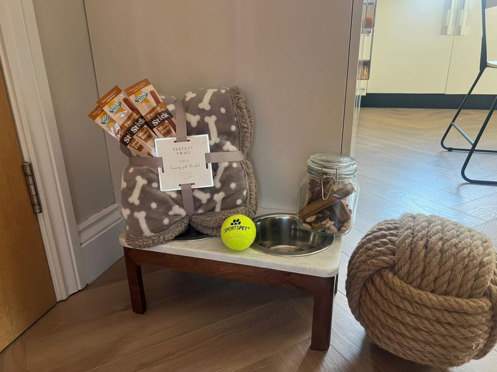 A pet area with a blanket, treats, food bowl and toys at Craster House in Seahouses