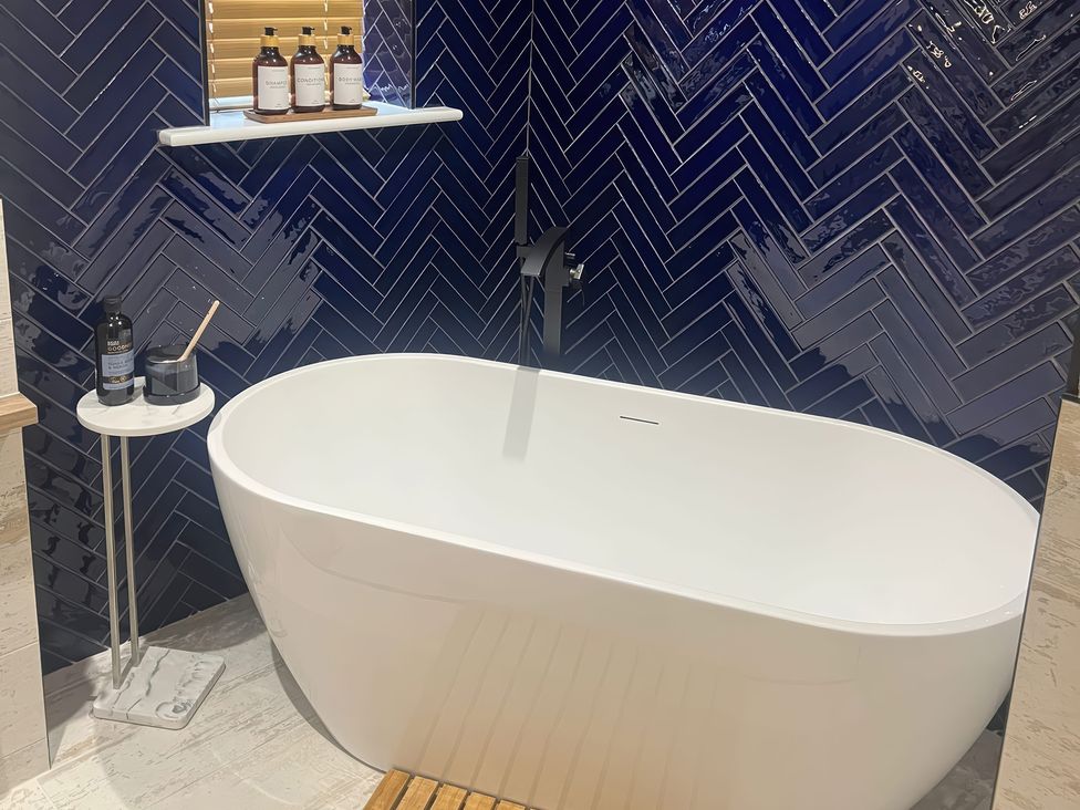 A bathroom with a bathtub and shelf at Craster House in Seahouses
