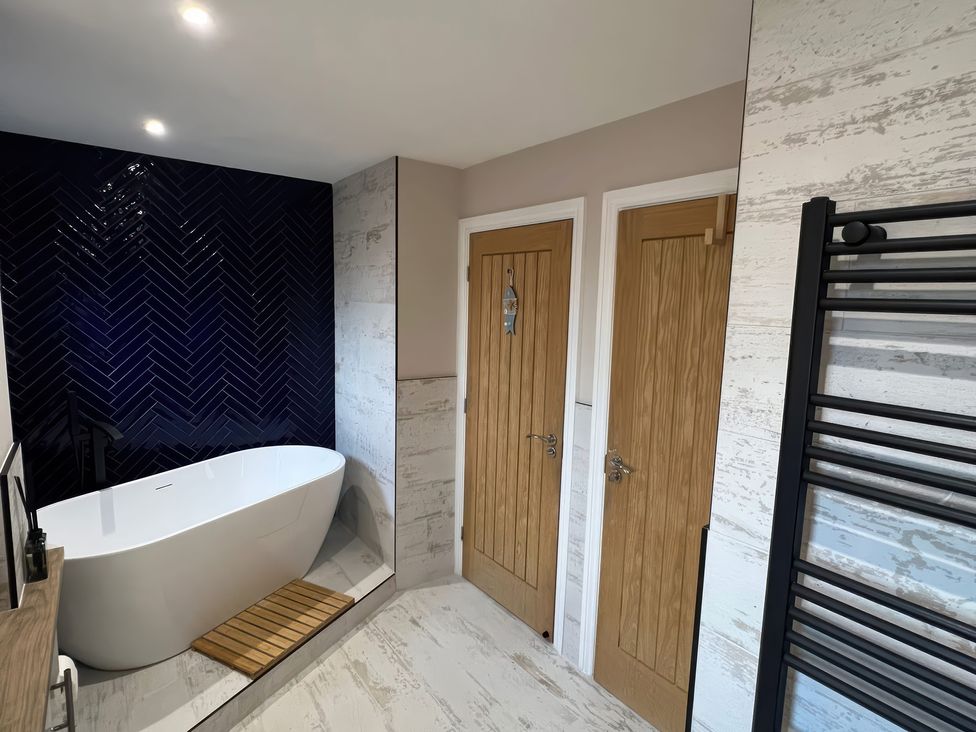 A bathroom with a bathtub and towel rack at Craster House in Seahouses