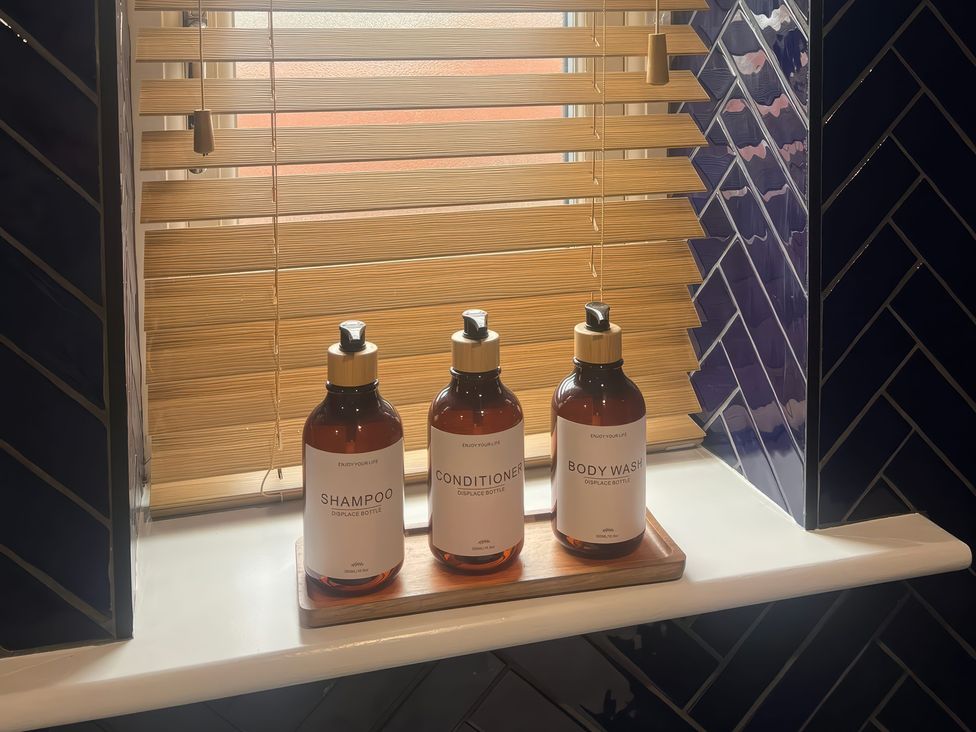 Bottles of shampoo, conditioner, and body wash on a windowsill at Craster House in Seahouses