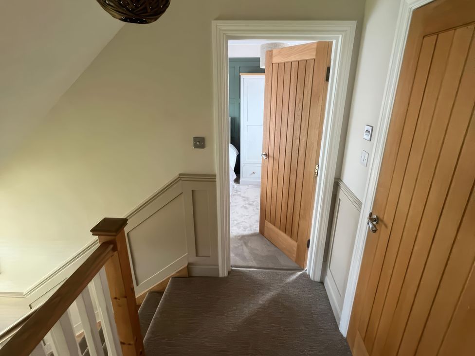 A hallway with stairs and doors at Craster House in Seahouses