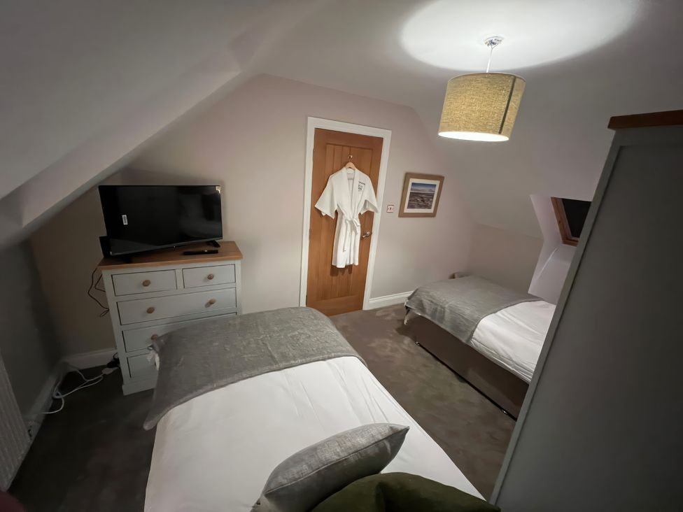 A bedroom with two beds and a television at Craster House in Seahouses
