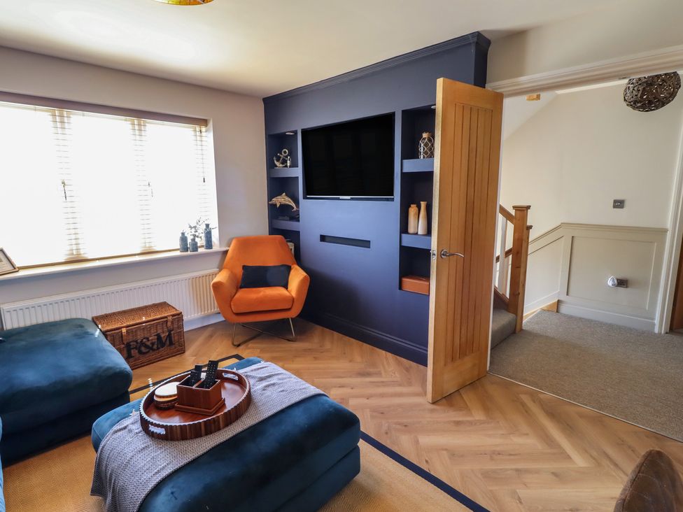 A living room with a television and guitar at Craster House in Seahouses