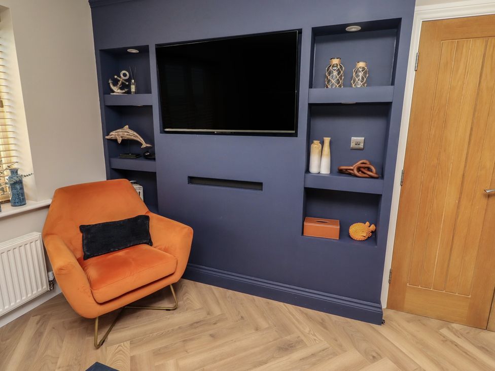 A living room with a television and an orange chair at Craster House Seahouses
