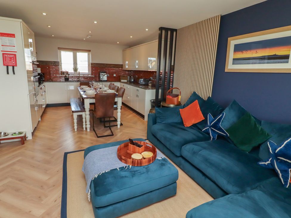 A living room with a sofa and dining area at Craster House in Seahouses