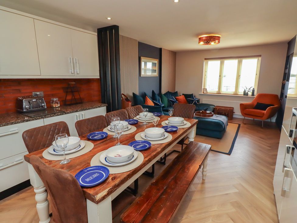 A dining room with a large table and upholstered chairs at Craster House in Seahouses