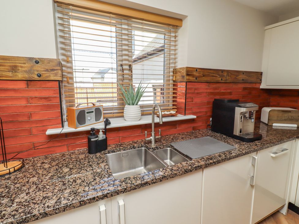 A kitchen with a sink, coffee machine, and speaker at Craster House in Seahouses
