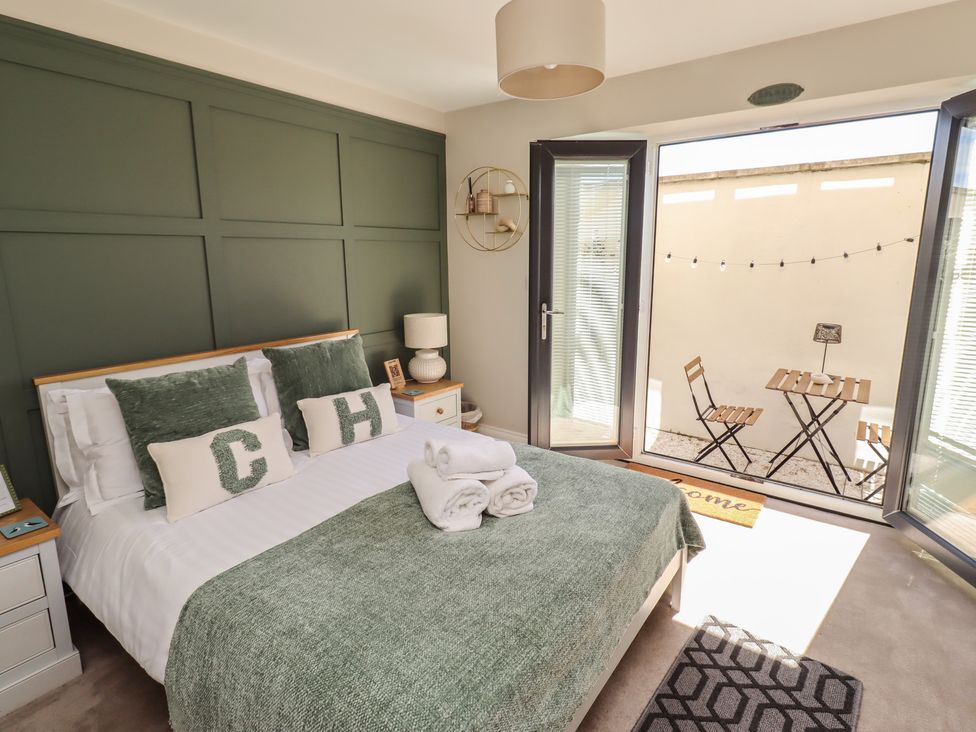 A bedroom with a bed and open doors leading to an outside area at Craster House in Seahouses