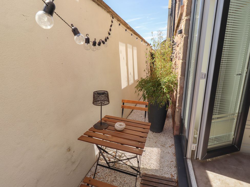 An outdoor seating area with a table and plants at Craster House in Seahouses