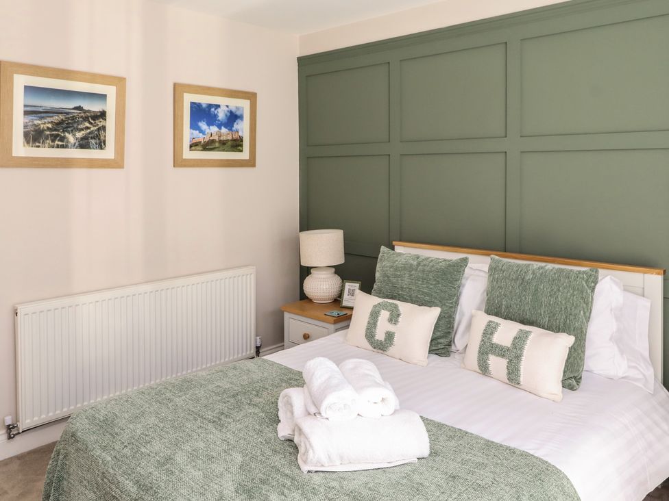 A bedroom with a bed and decorative pillows at Craster House in Seahouses