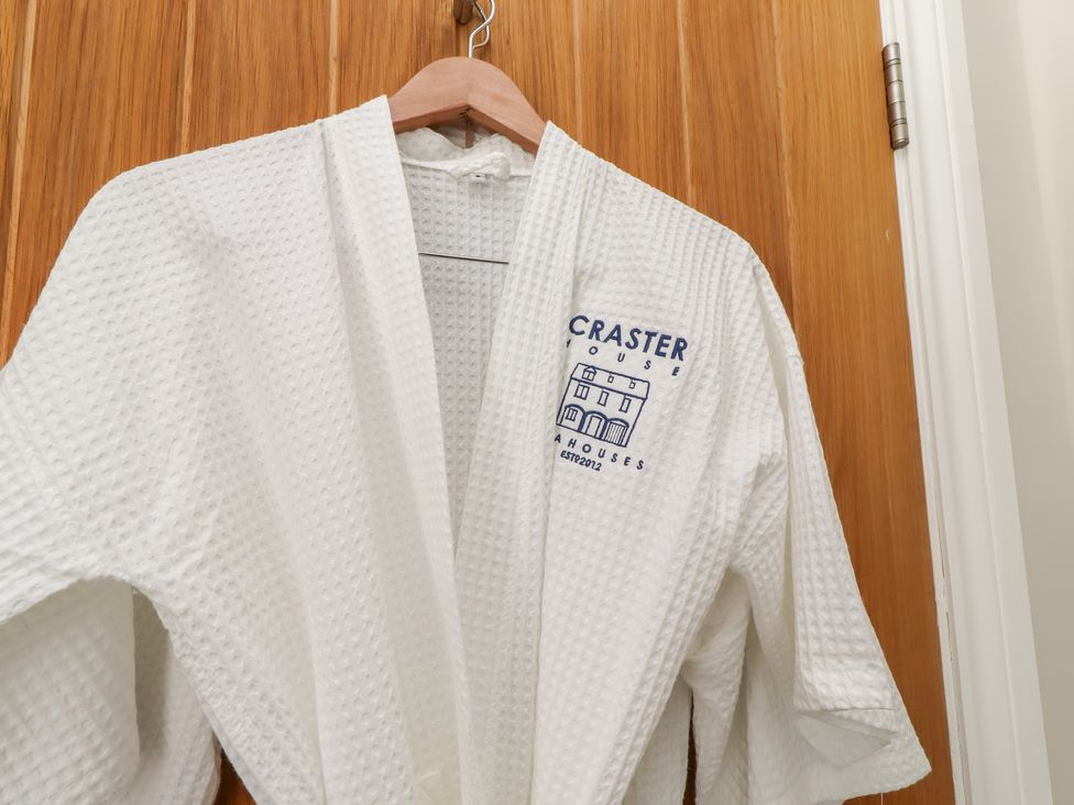 A bathrobe hanging on a wooden door at Craster House in Seahouses