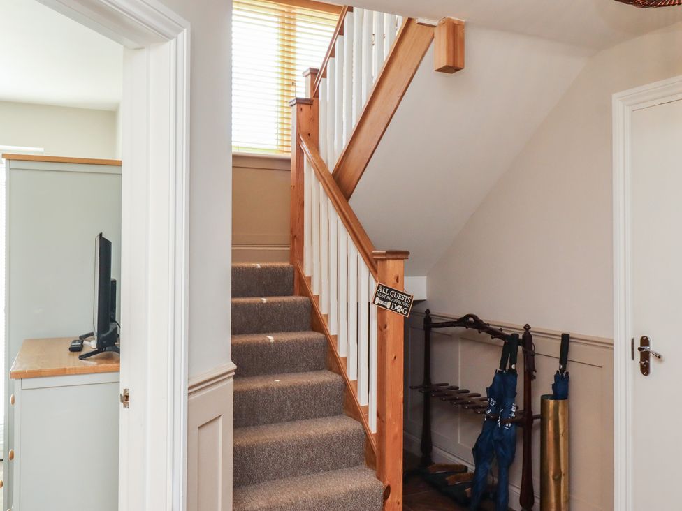 A hallway with stairs and a computer desk at Craster House Seahouses