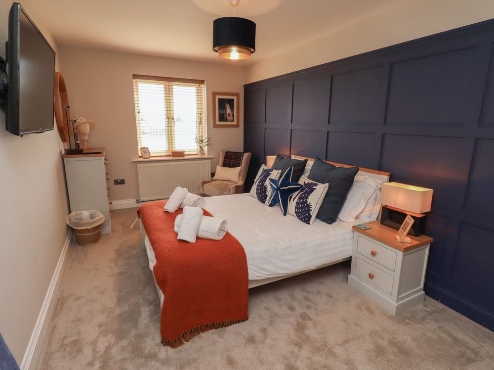 A bedroom with a bed, bedside table, and television at Craster House in Seahouses