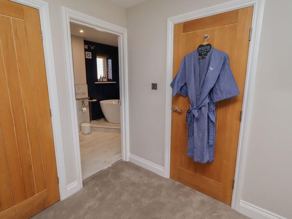 A bathroom entrance with a robe hanging on the door at Craster House in Seahouses