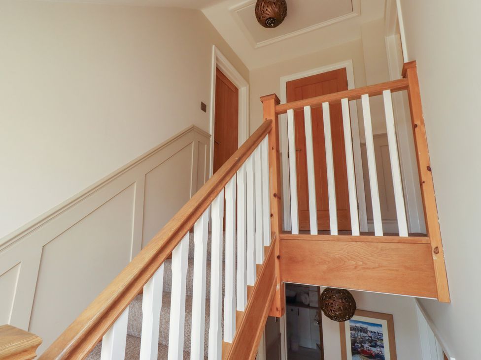 A staircase with wooden banister and doors at Craster House in Seahouses