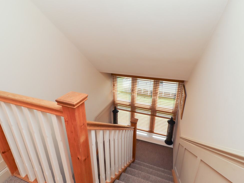 A staircase with wooden banister and blinds at Craster House in Seahouses