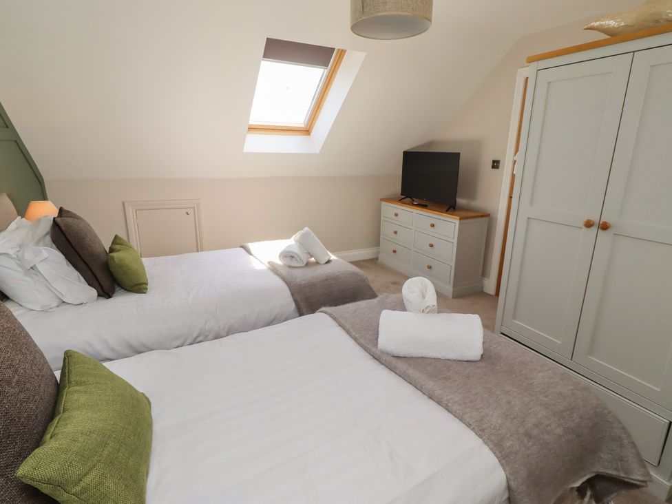 A bedroom with two beds and a television at Craster House in Seahouses