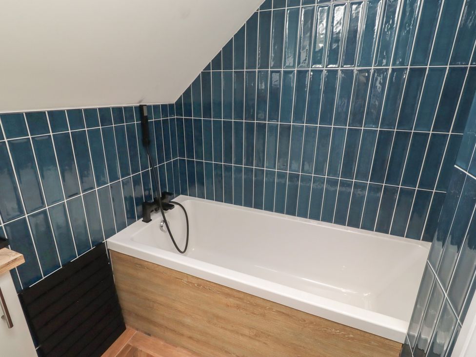 A bathroom with a bathtub and blue wall tiles at Craster House in Seahouses