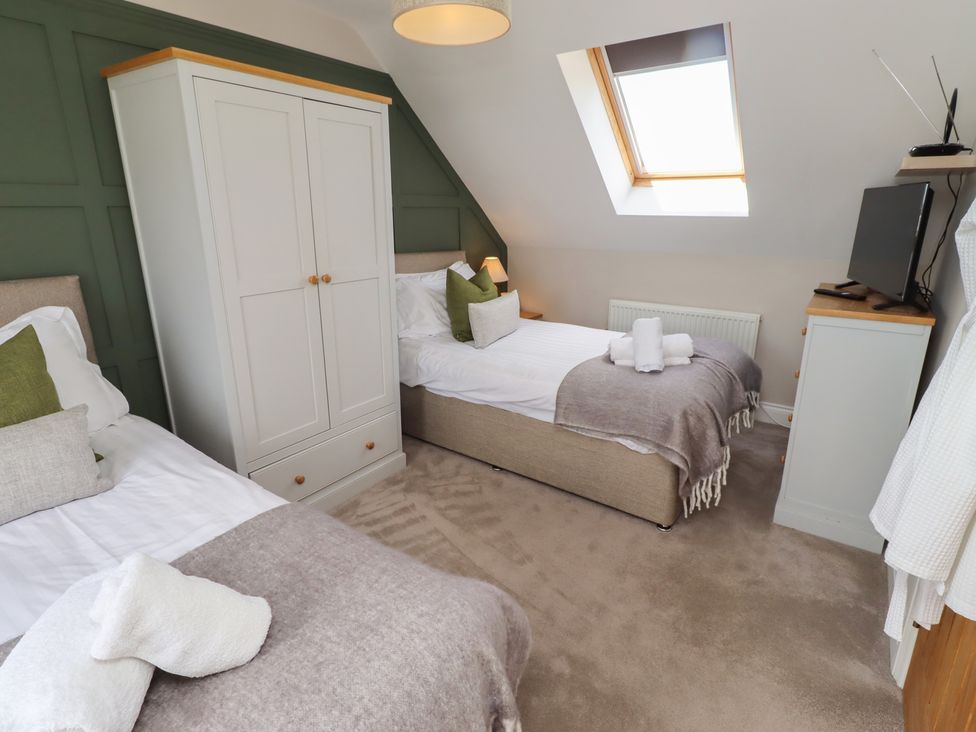 A bedroom with two beds and a wardrobe at Craster House in Seahouses