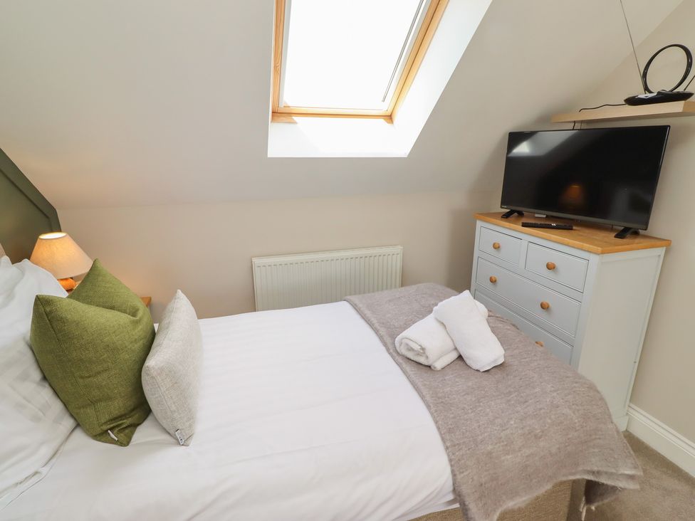 A bedroom with a bed, TV, and drawer unit at Craster House in Seahouses