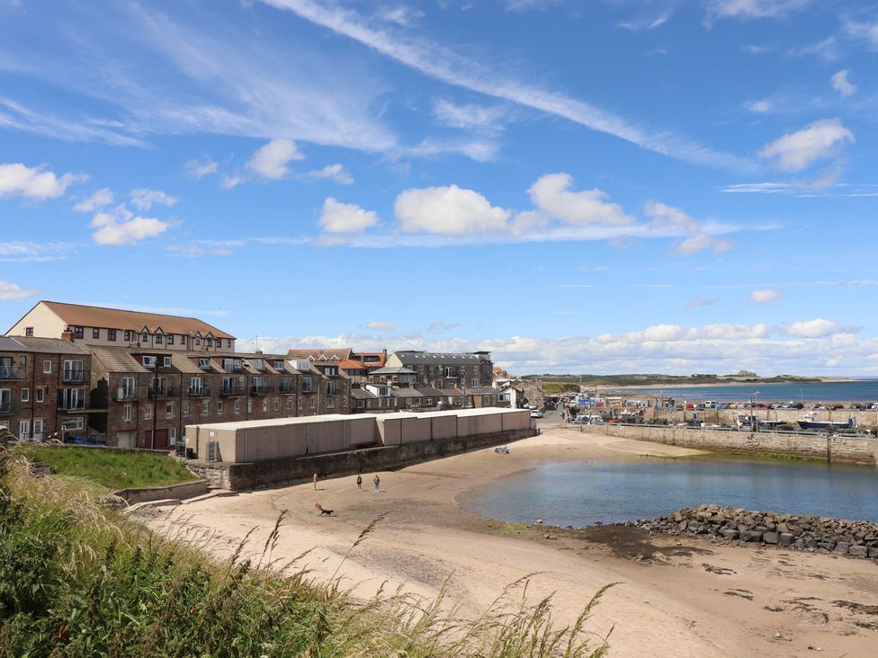 Buildings along the beach with boats and coastline at Craster House Seahouses