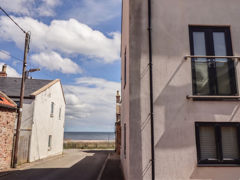 A view of a road with buildings and the ocean at Craster House in Seahouses
