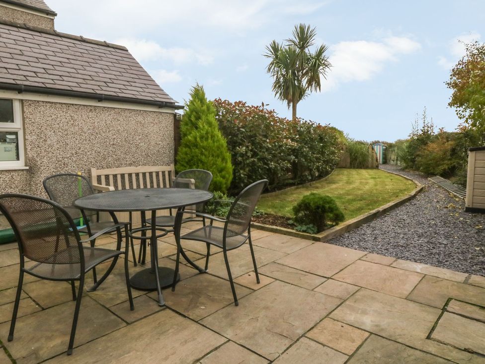 A garden with a table and chairs at Rhianfa in Llanfairpwllgwyngyll