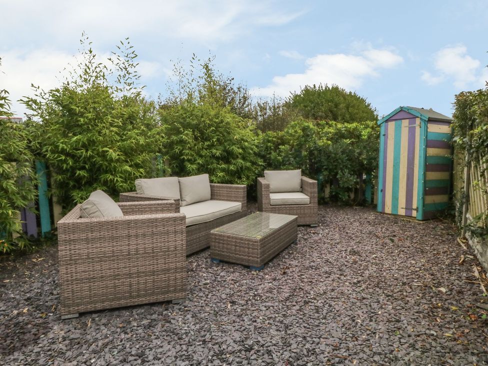 A garden with seating area and a colorful shed at Rhianfa in Llanfairpwllgwyngyll