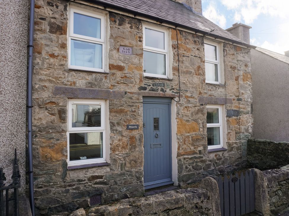 A stone cottage with windows and a blue door at Rhianfa Newborough