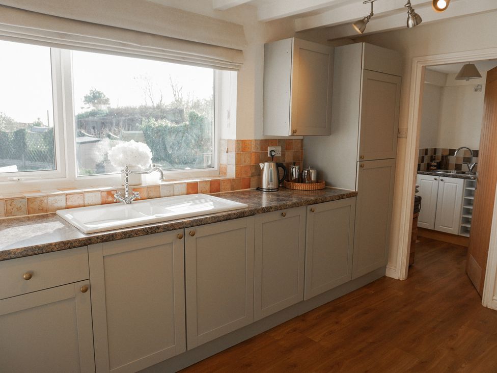 A kitchen with cabinets and sink at Rhianfa Newborough