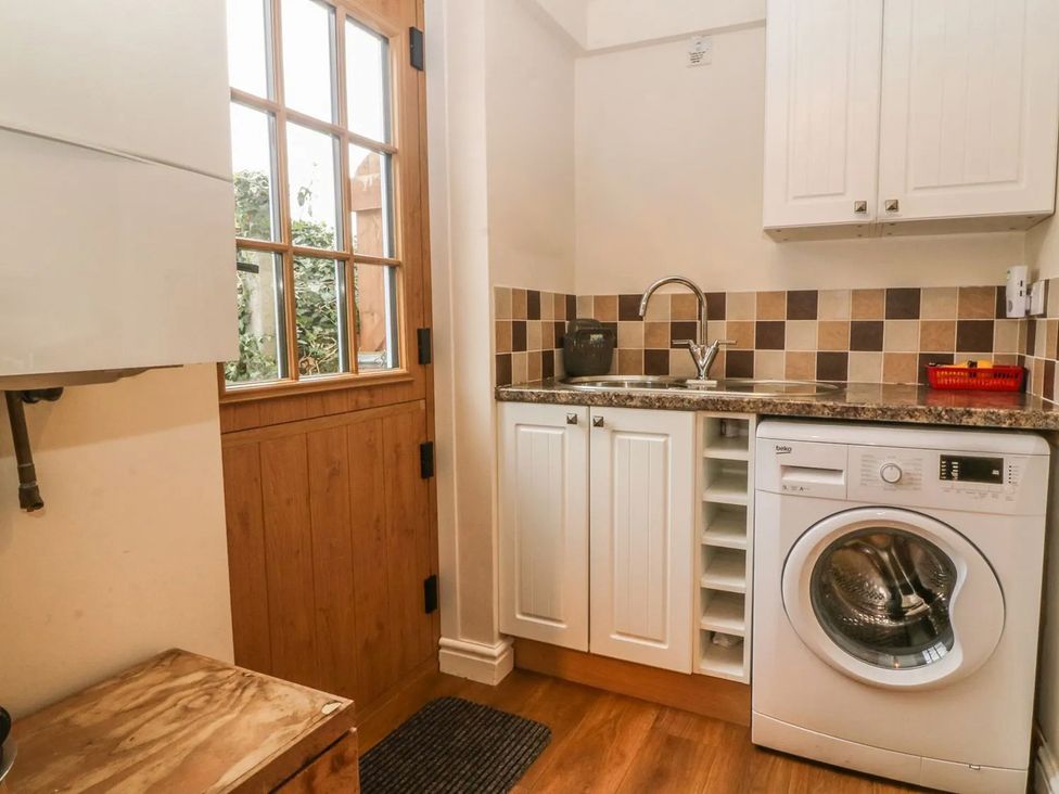 A laundry room with a washing machine and sink at Rhianfa in Newborough