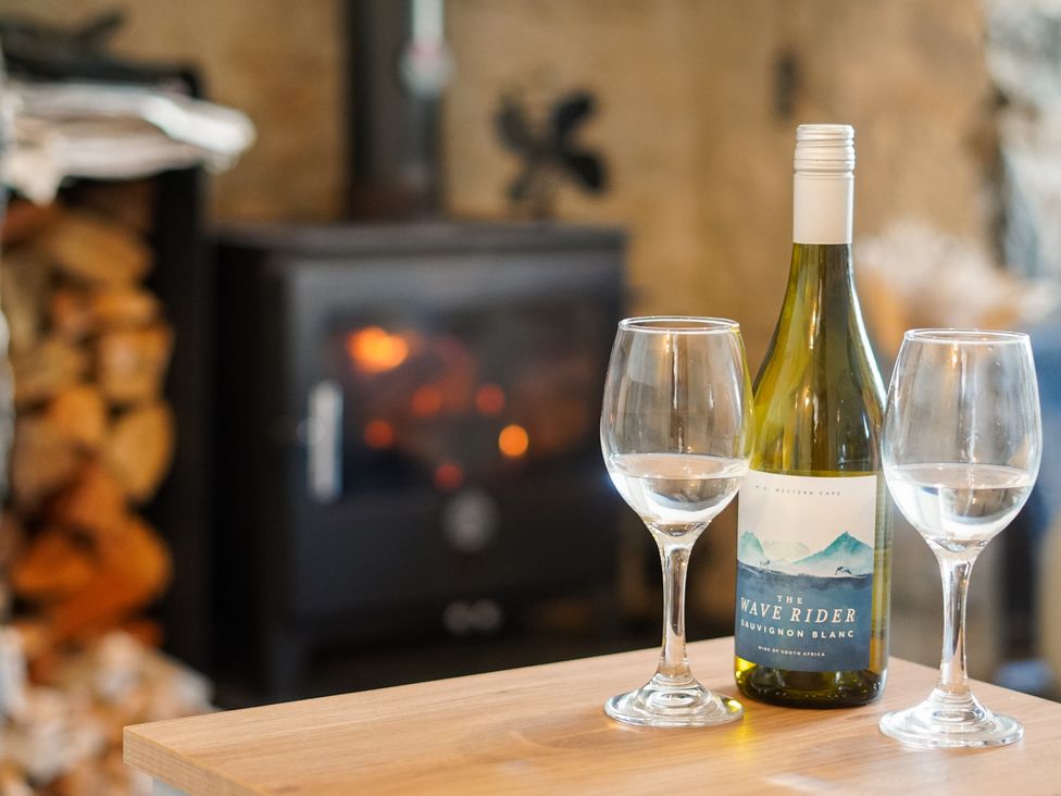 A living room with wine and glasses on a table at Rhianfa in Newborough