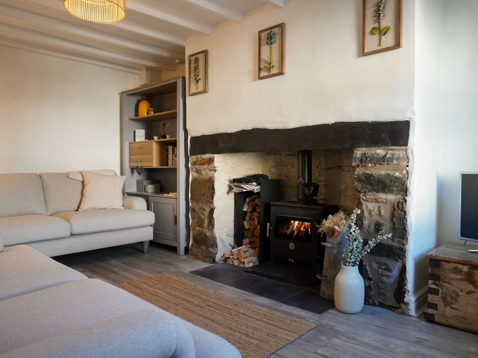 A living room with a fireplace and sofa at Rhianfa in Newborough