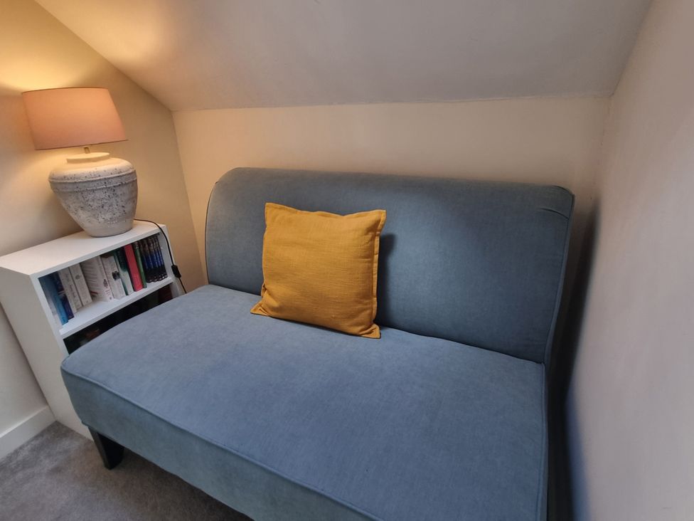 A sofa with a yellow cushion and a lamp in a living room at The Coach House in Castle Cary
