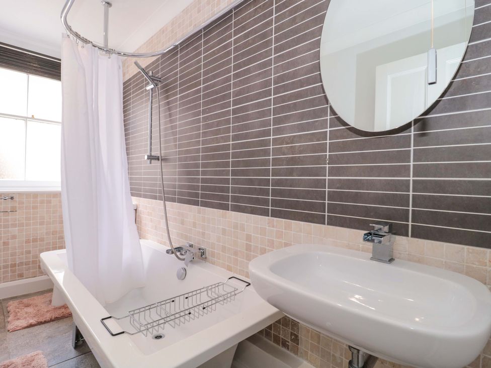 A bathroom with a bathtub, sink, and mirror at Flat 2 Battledown Grange in Cheltenham