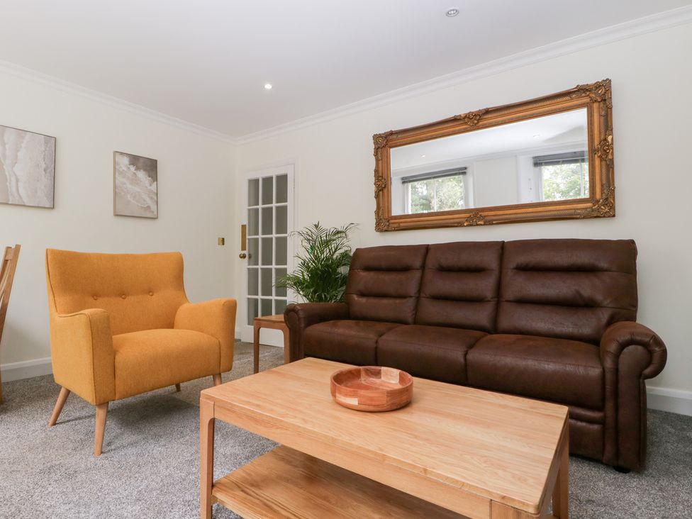 A living room with a sofa, armchair, coffee table, and mirror at Flat 2 Battledown Grange Cheltenham