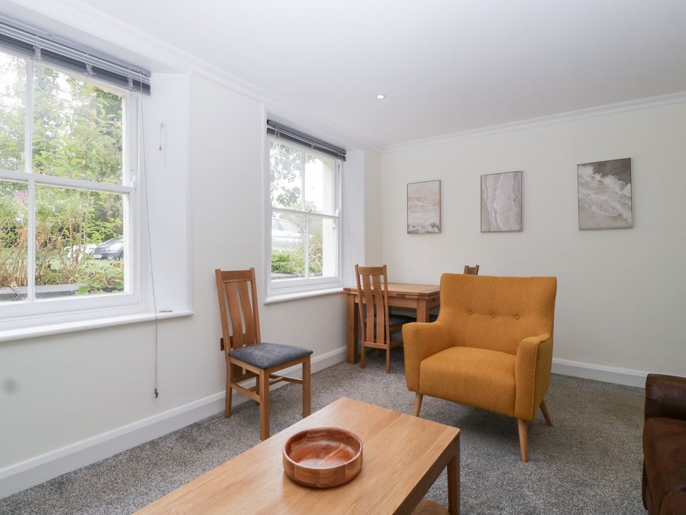 A living room with an orange chair and wooden table at Flat 2 Battledown Grange in Cheltenham