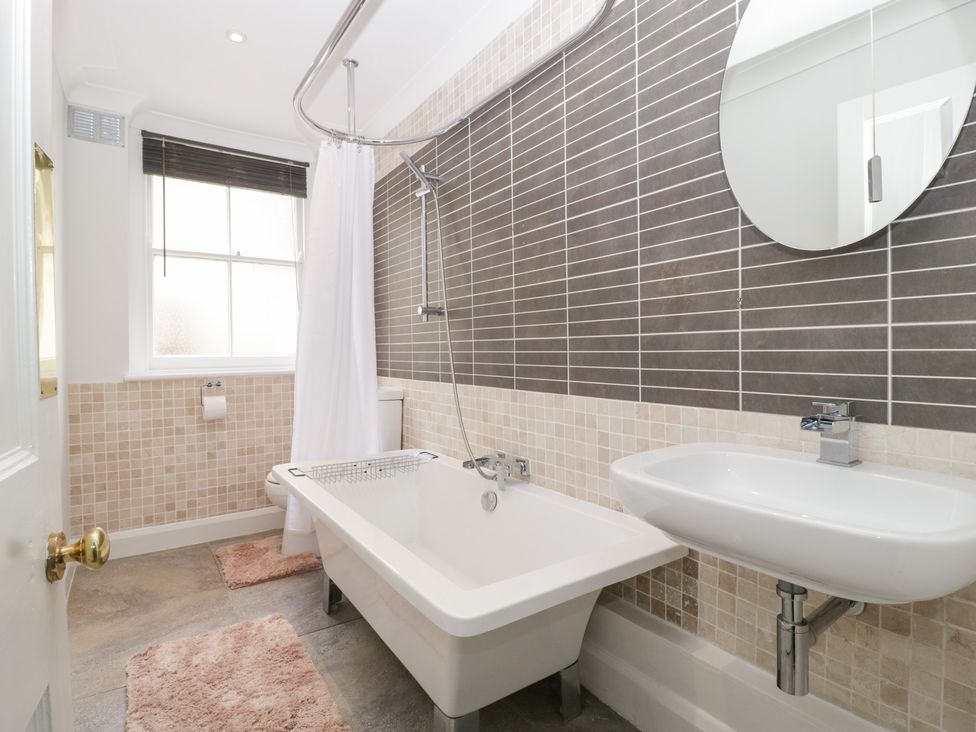 A bathroom with a bathtub, washbasin and mirror at Flat 2 Battledown Grange, Cheltenham