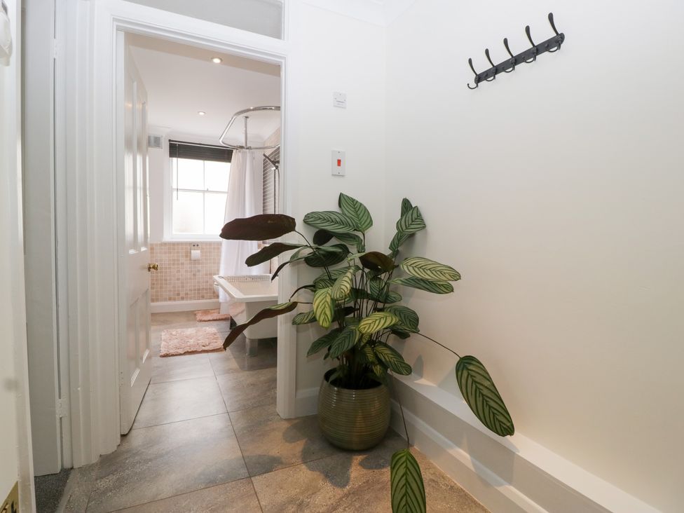 A hallway leading to a bathroom with a bathtub and plant at Flat 2 Battledown Grange Cheltenham